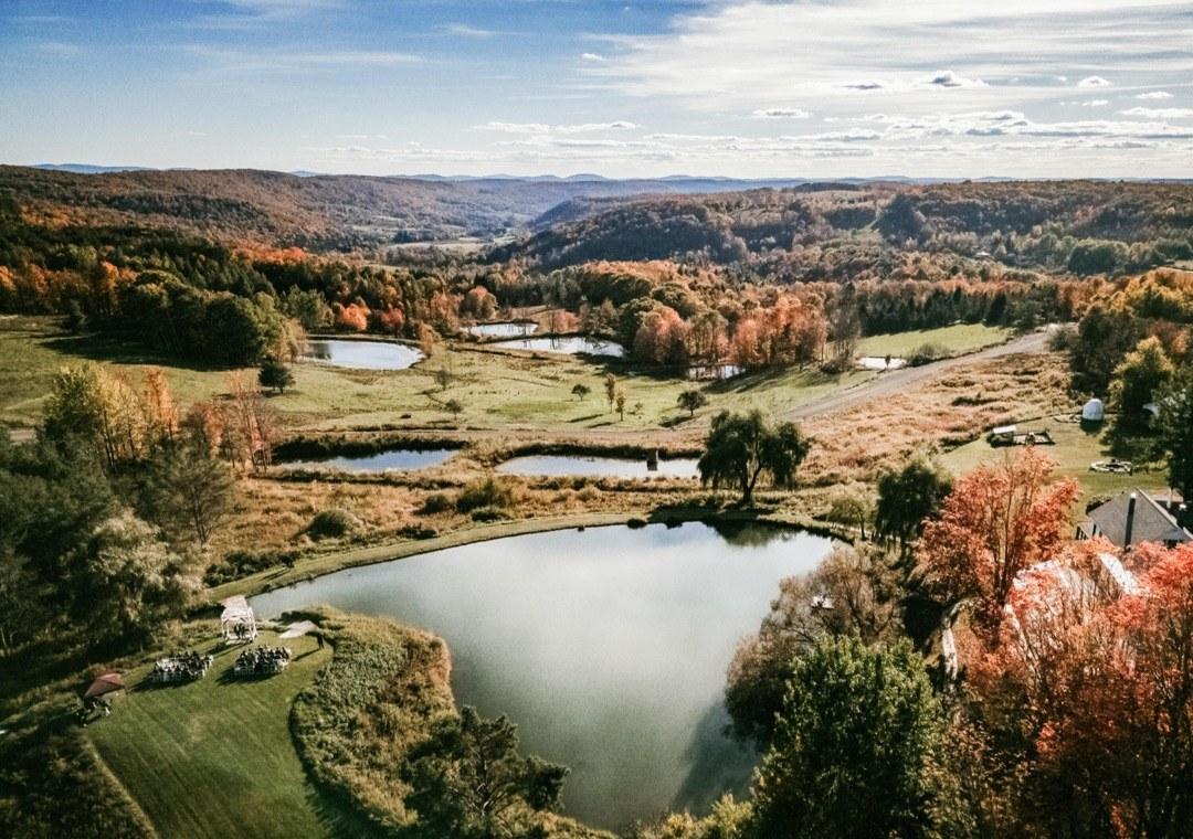 Aerial view of Twelve Ponds, showing a series of ponds and meadows surrounded by autumn forest and distant mountains.