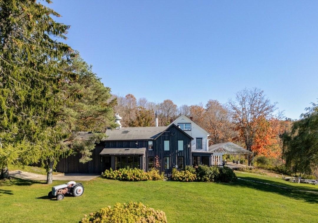 The dark-clad farmhouse at Twelve Ponds with an antique tractor on the front lawn.
