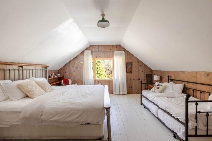 Attic room in the farmhouse with pine walls, painted floors and gabled ceiling.