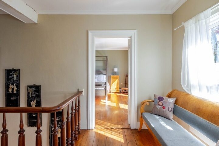Upstairs landing in the farmhouse with turned banister, wide-plank floors and a window bench.