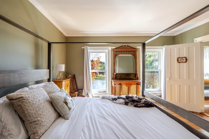 Farmhouse room with sage walls, antique vanity and a window onto the pond.