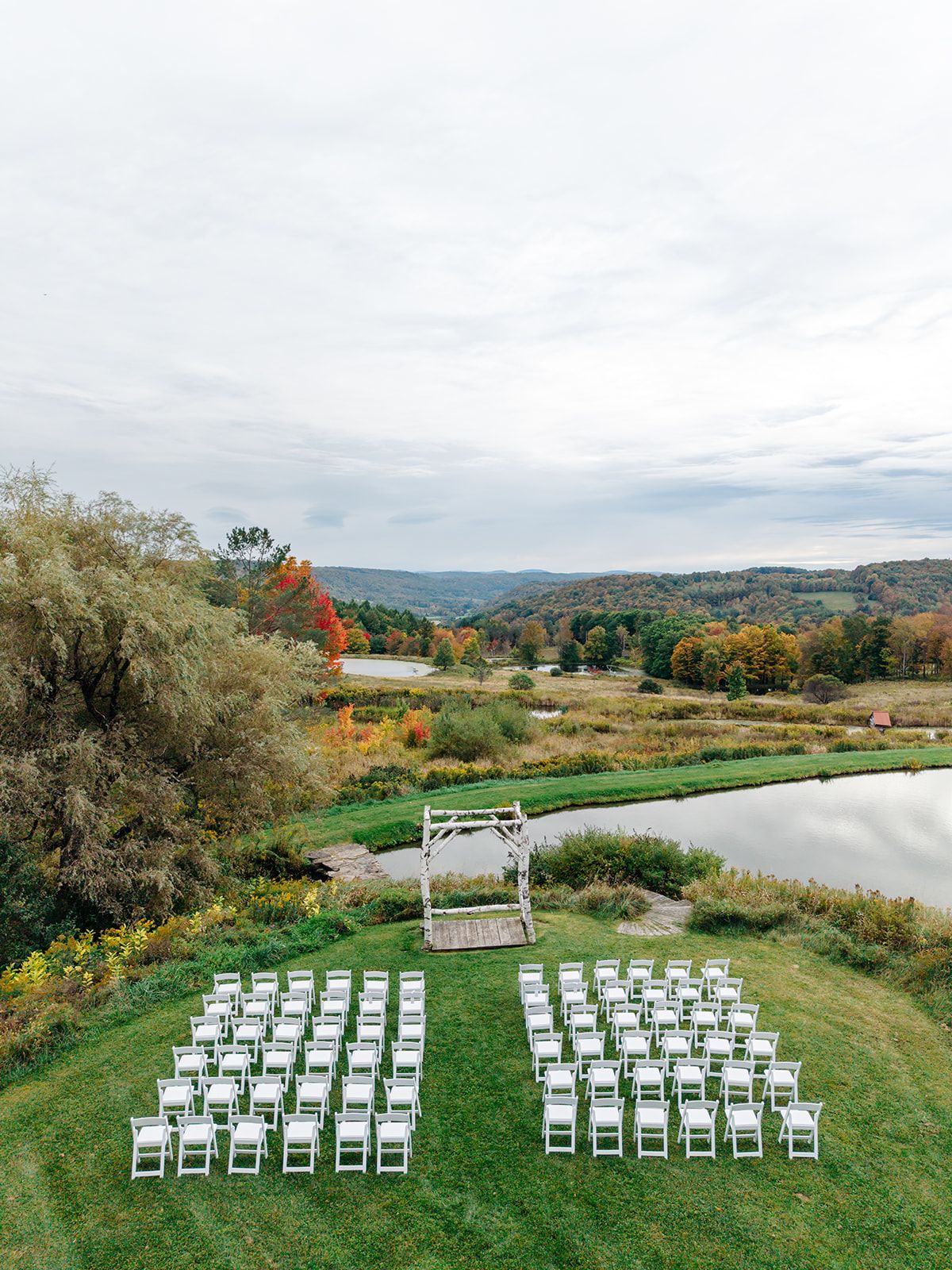 White ceremony chairs set on the lawn beside a pond at Twelve Ponds.